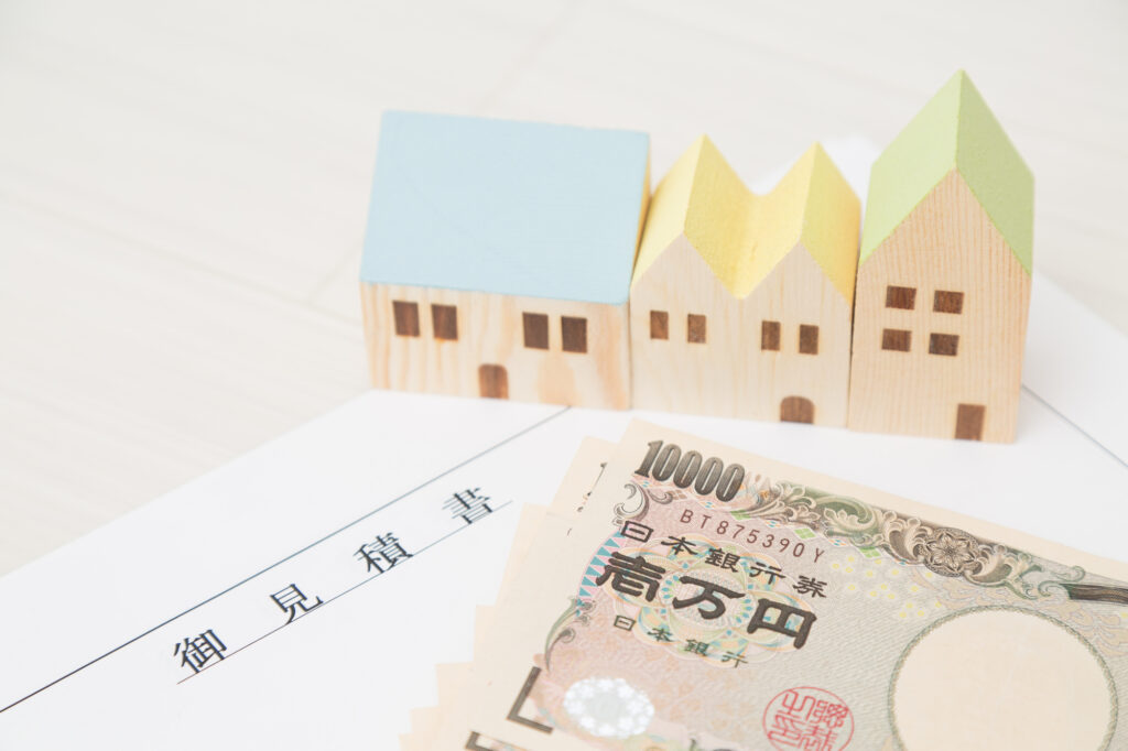 アパートの見積もり書と家の形をした積み木、一万円の札束
