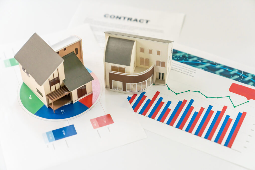 2つの住宅模型とグラフが印刷された書類
